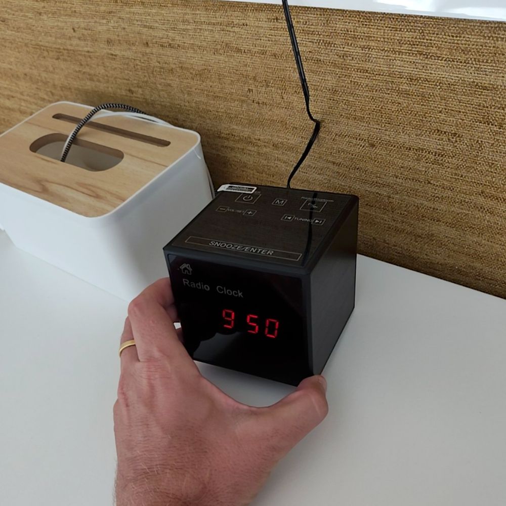 Reloj despertador espía WiFi en la mano, mostrando su tamaño real